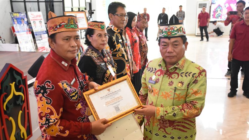 Bupati Kapuas Muhammad Wiyatno menyerahkan penghargaan kepada perangkat daerah, kelurahan, serta desa terbaik dalam pengelolaan layanan informasi, pengaduan, dan kehumasan Tahun 2025 pada kegiatan Bimtek PPID di Hall Rujab Bupati Kapuas, Jumat (6/2/2026).